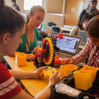 Image of kids working with a STEM education kit with computers and a mechanical wheel.
